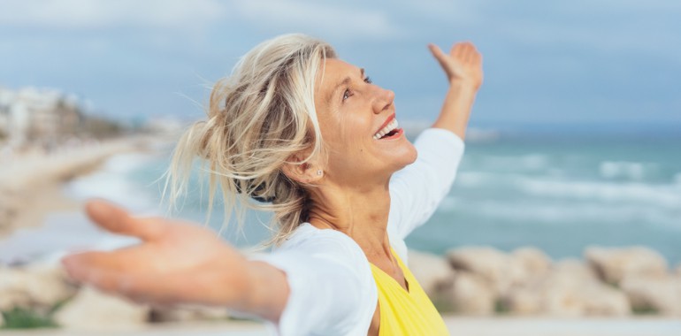 Joyful emotionally fit woman over 40 with arms outstretched